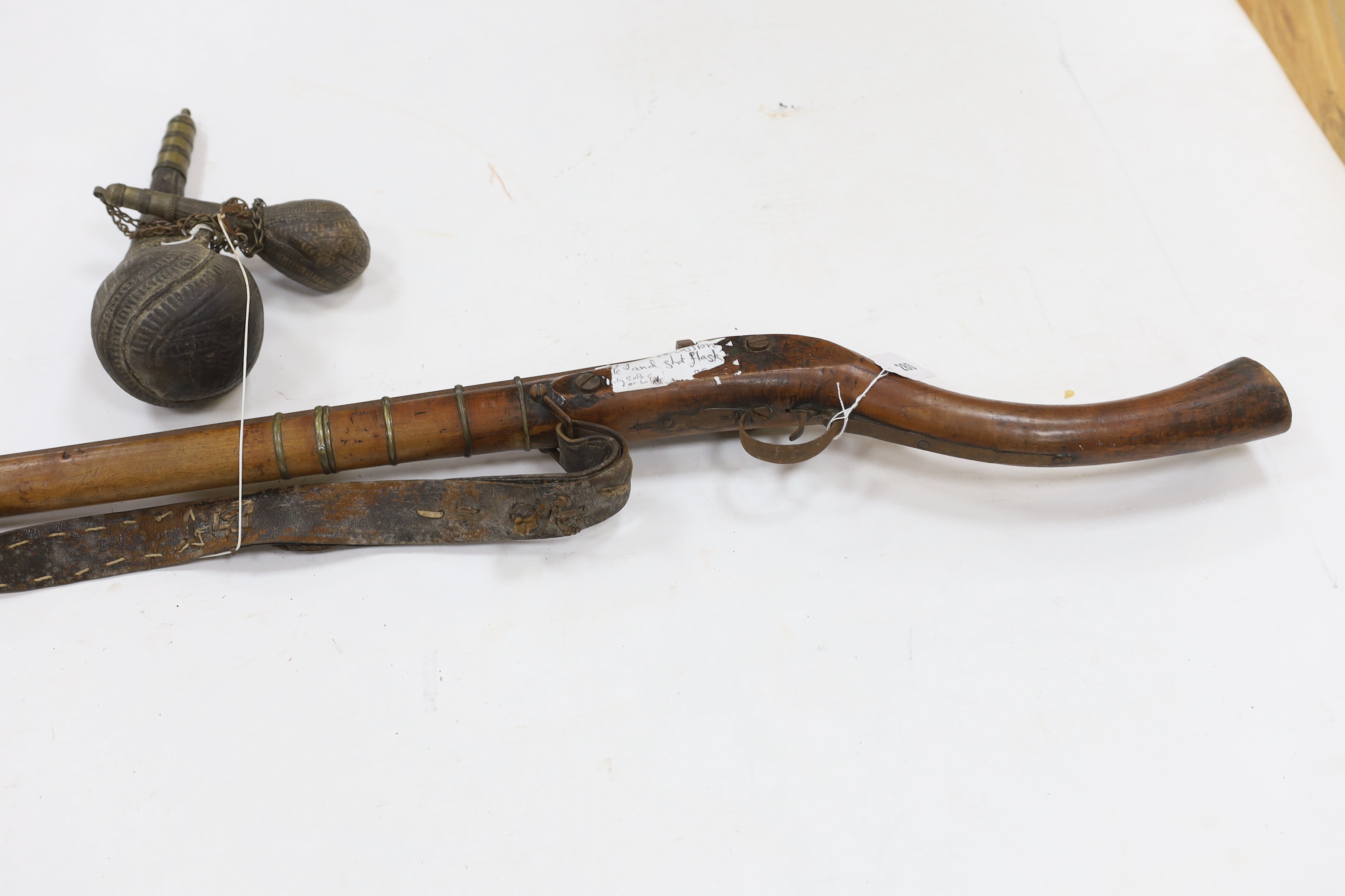 An Afghan percussion rifle with octagonal barrel and brass mounts, barrel 105.5cm, together with two leather powder flasks